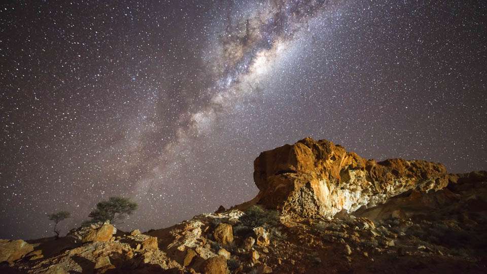 The milky way glistening over a rugged rocky outcrop