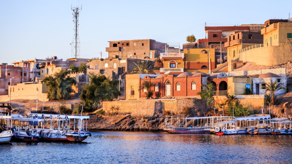 Wooden boats carrying passengers docked along the Nile River at the Temple of Philae in Aswan, Egypt 
