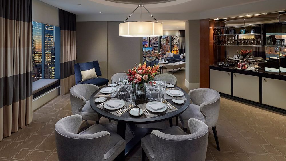 Six grey velvet dining chairs around a dining table in the Crown Towers suite dining room.